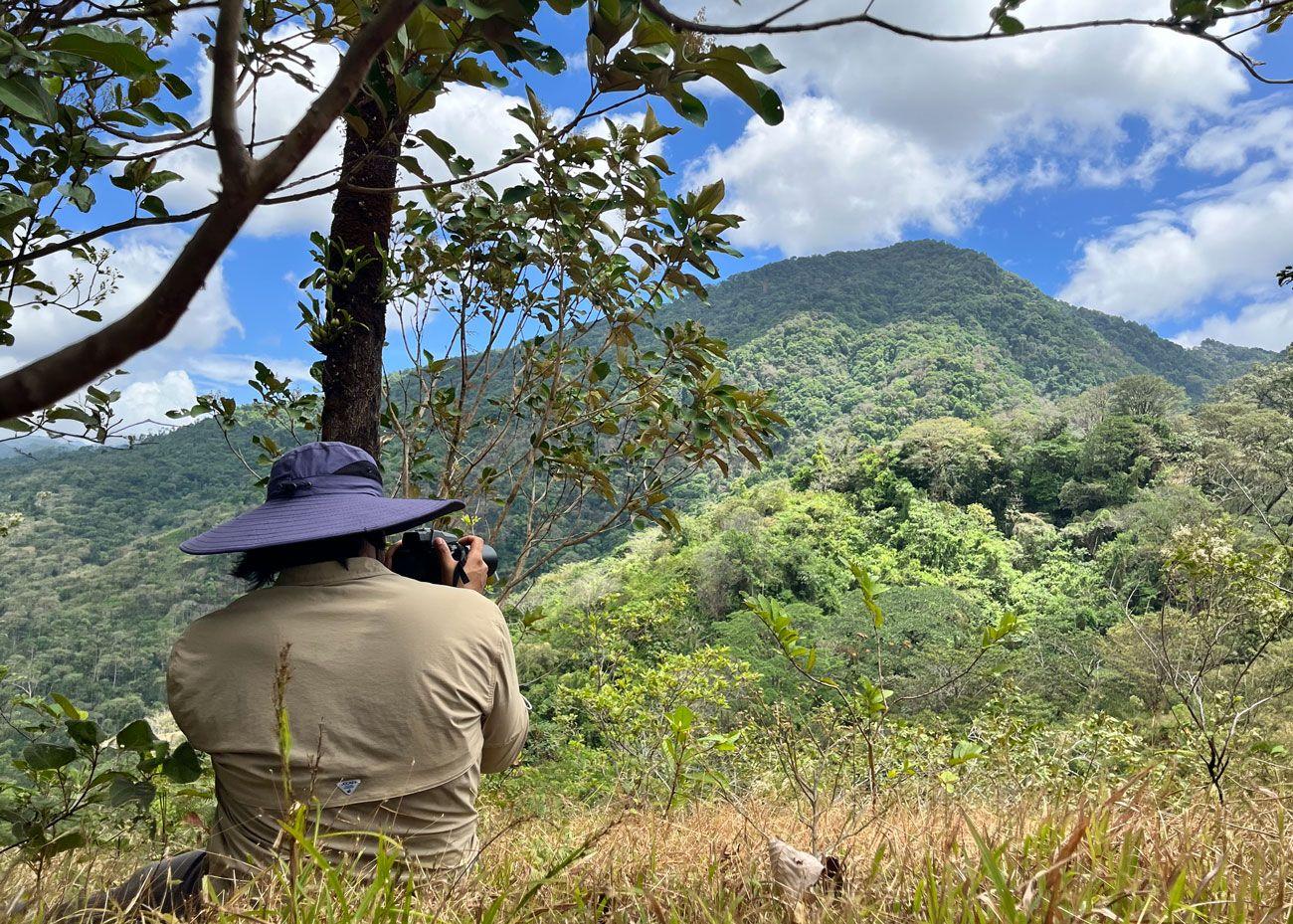 Persona fotografiando el paisaje montañoso de Cerro Hoya durante una expedición de avistamiento de aves en Azuero.