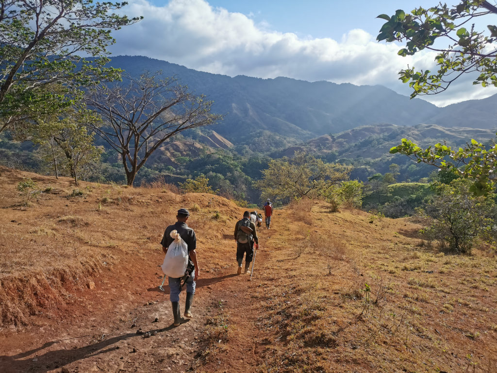 Men walking towards a beautiful mountains covered in rainforest 
